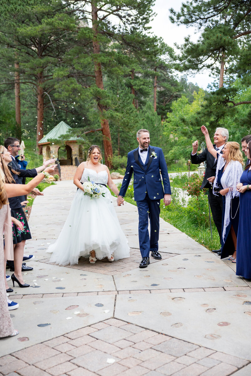 Bride and groom hold hands while happily walking through their guests throwing heart shaped leaves