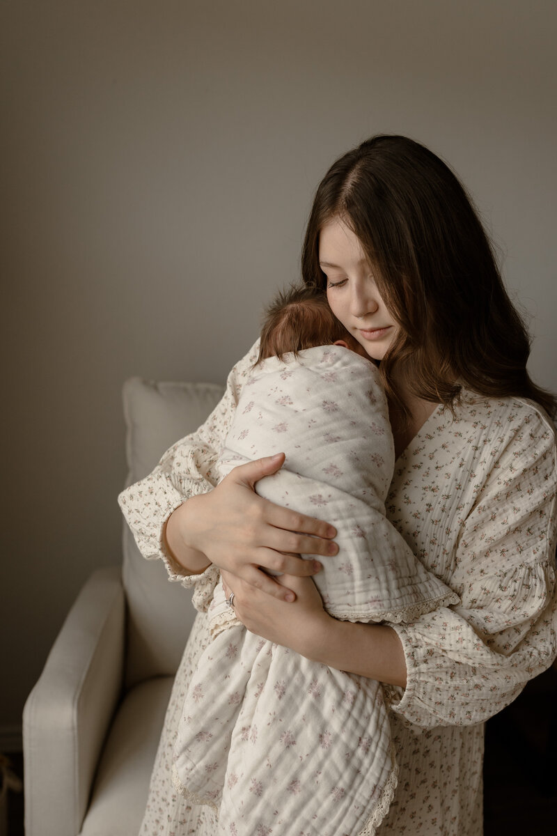 Mom holding her newborn up near her chin