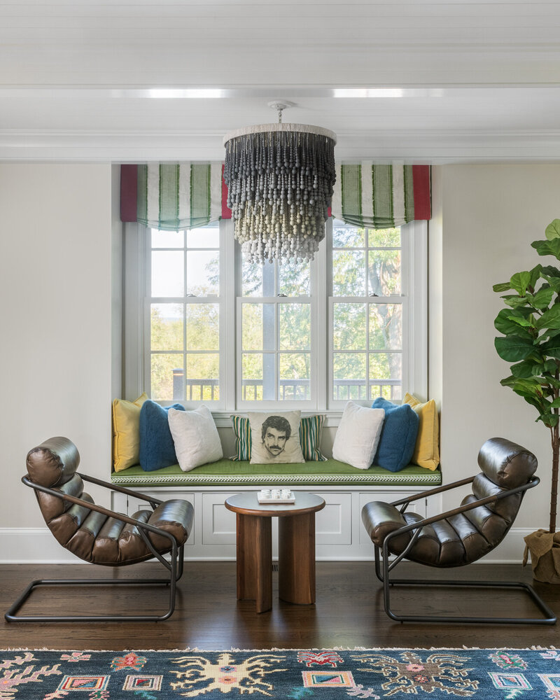 colorful window seat with two brown armchairs and a chandelier