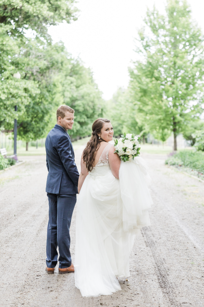 Bride in a beautiful white gown and groom in a stylish black tuxedo walking together to their wedding reception, holding hands and smiling joyfully.