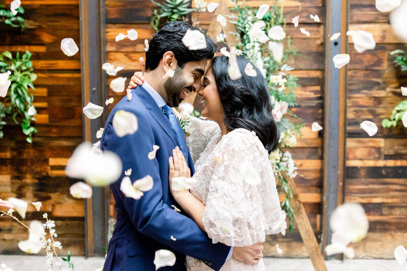 Couple kissing as flower petals fall around them at their Hudson Valley micro wedding