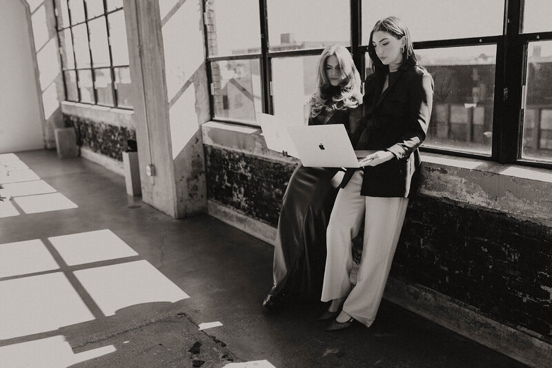 Two business owners looking at and working from their laptops posing for a photo