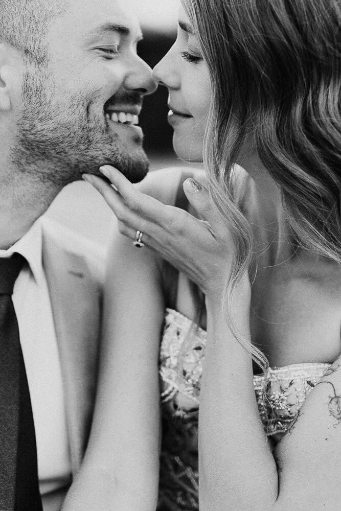 Un couple souriant, se rapprochant l'un de l'autre dans une pose intime, l'homme portant une chemise et la femme une robe élégante. Photographie par Sonia Bourdon photographe de mariage