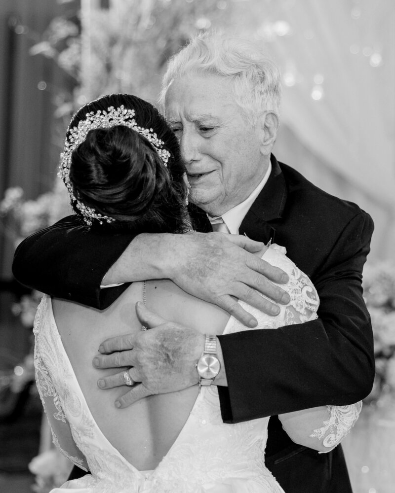Candid photo of grandfather crying and hugging the bride. 