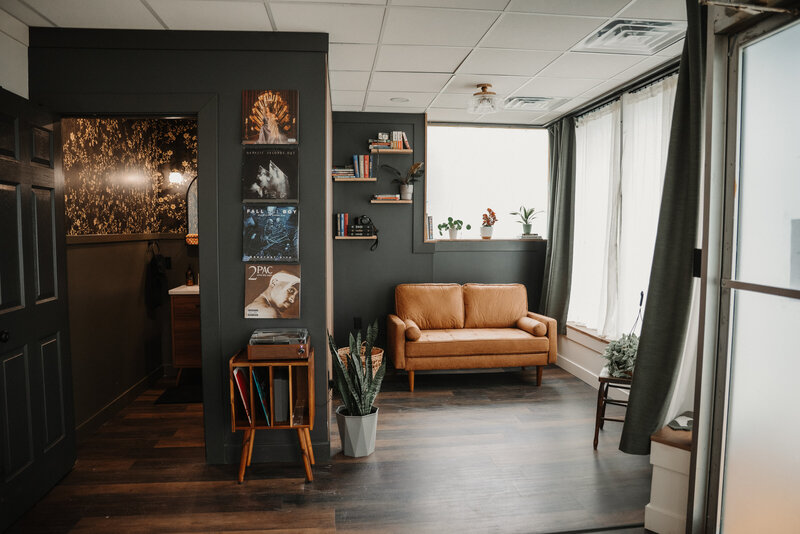 moody corner of a bloomington illinois photography studio for rent near downtown bloomington. record wall and tan couch with large natural light windows fill the space