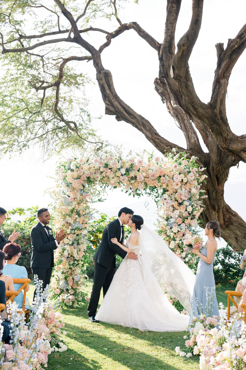 Wedding and Elopement Photography, couple kissing under large floral arch