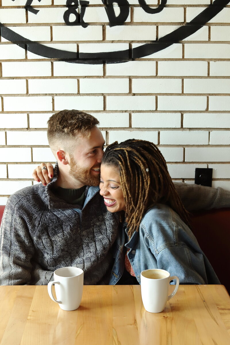 man and woman posing for their engagement session in a south carolina coffee shop