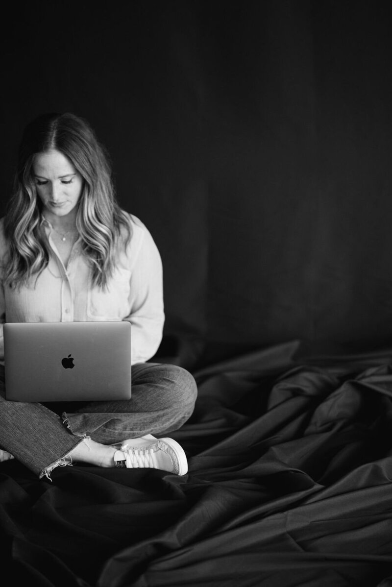 Woman sitting down and typing on a laptop