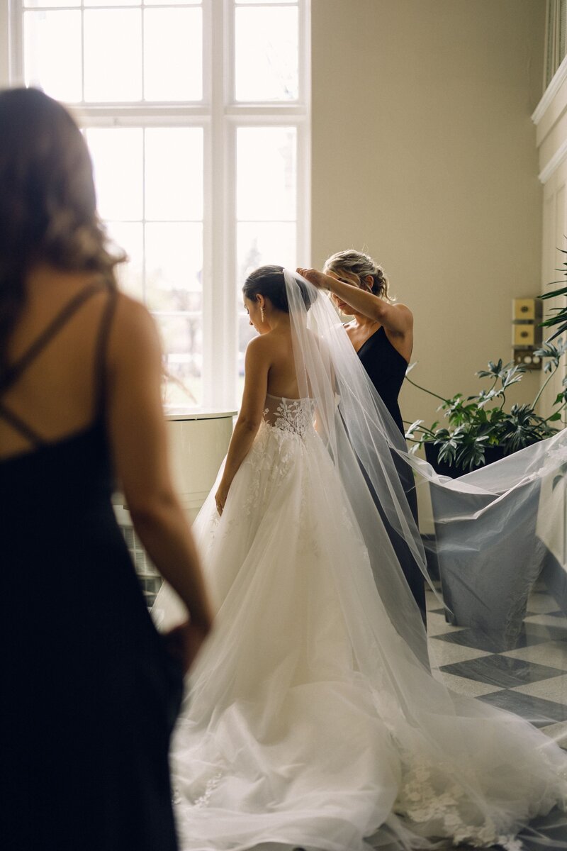 A bridesmaid helps the bride adjust her veil before the wedding ceremony.