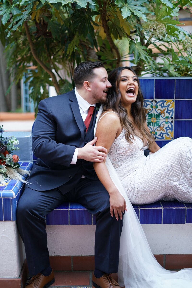 Weddings in Newport Beach bride and groom sitting on tile bench and laughing together
