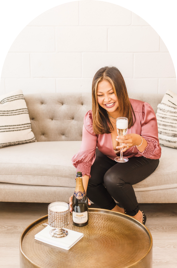 woman in pink laughing sitting on a couch  holding wine glass