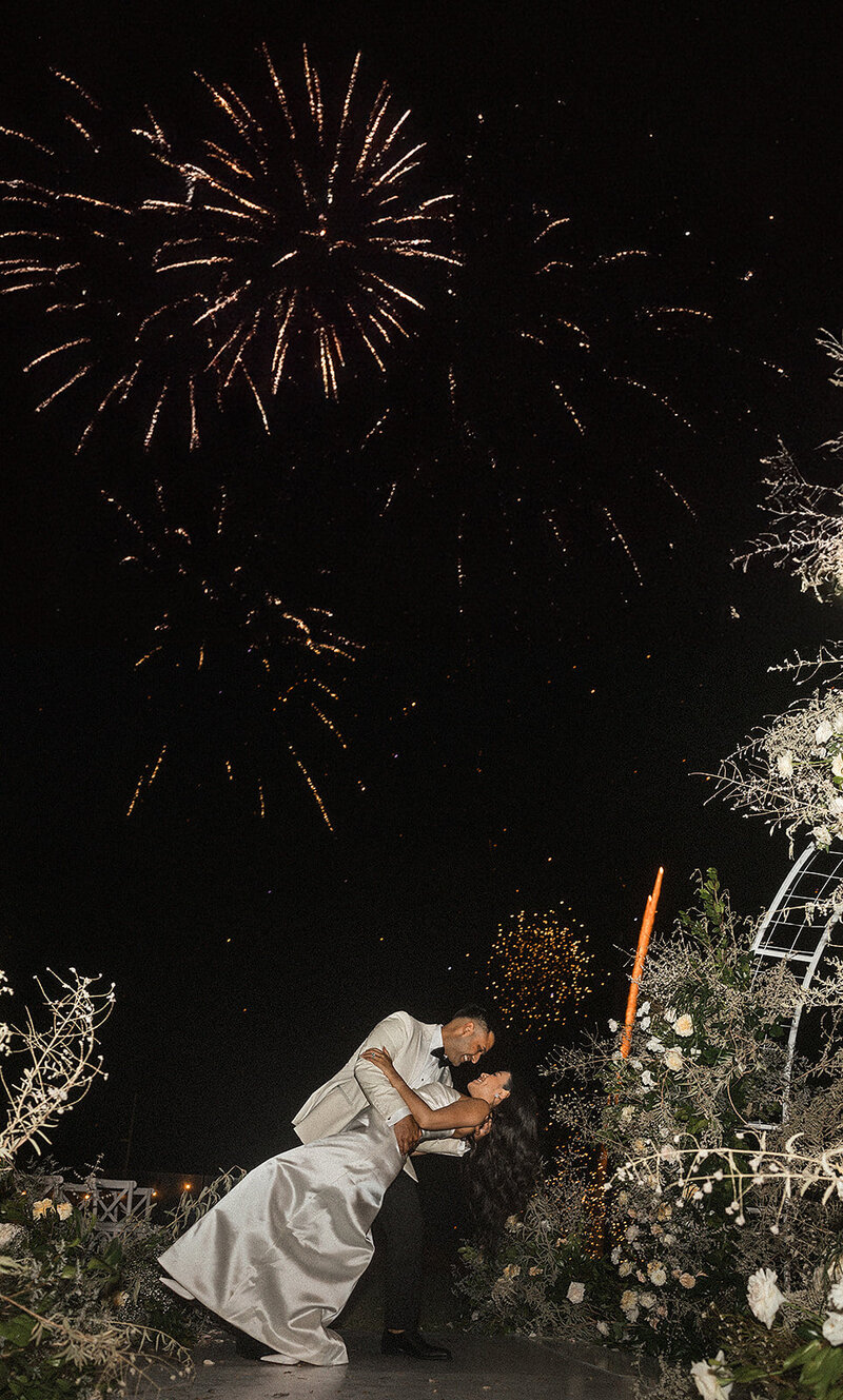 Groom dancing with bride with fireworks in the background