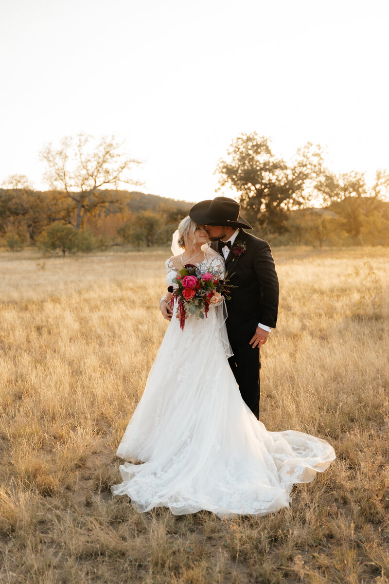 bride and groom kissing in field