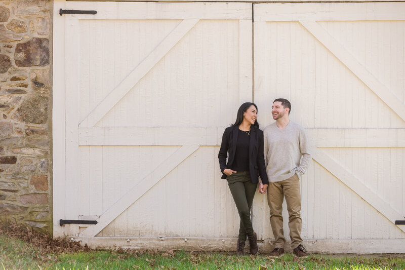 Couple standing against a barn door at Valley Forge National Historical Park, adding a charming rustic touch to their engagement photos.