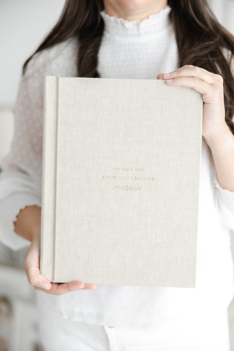 woman holds linen-covered heirloom photo album