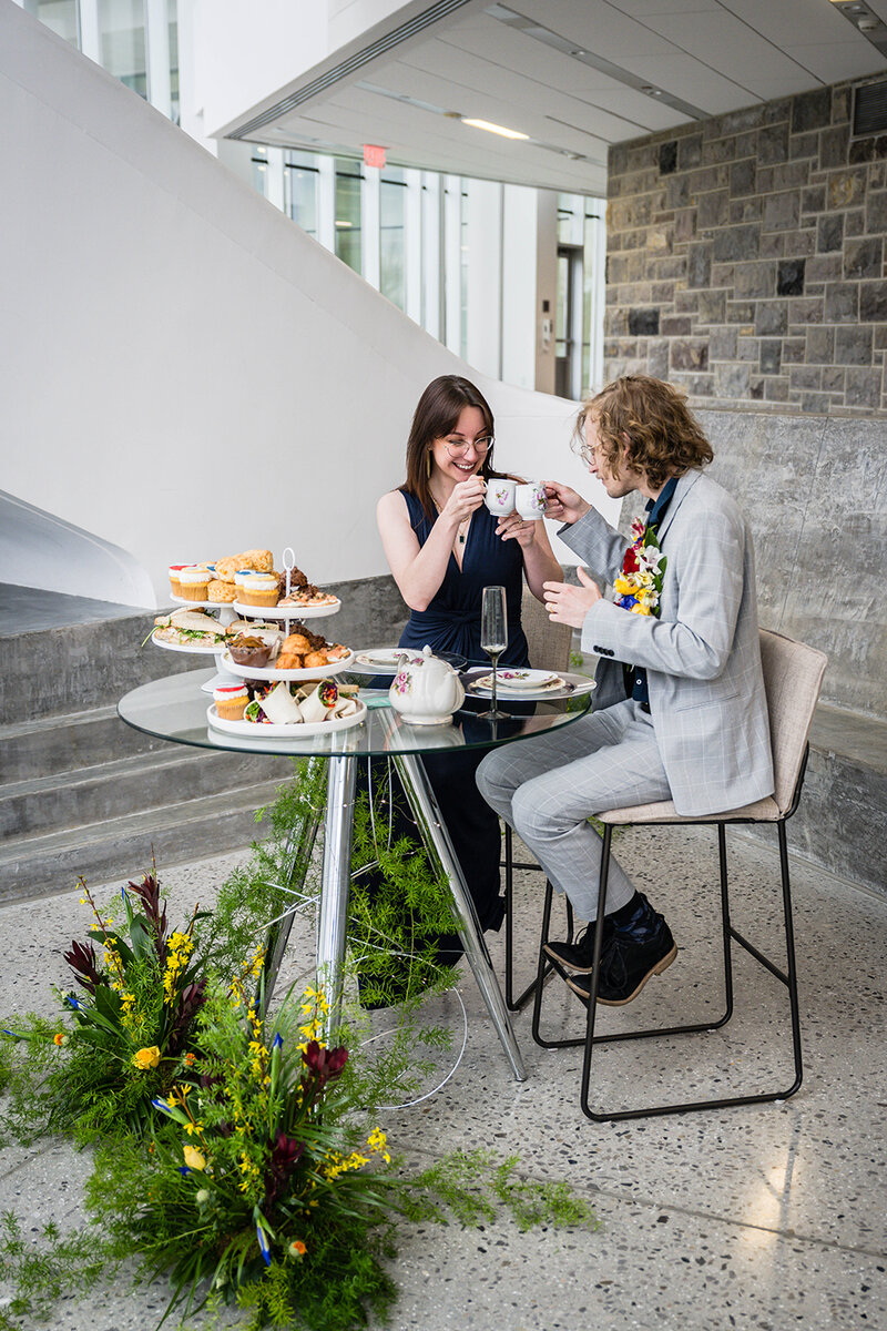 A couple sits inside of Moss Arts Center on their elopement day for dinner and tea.