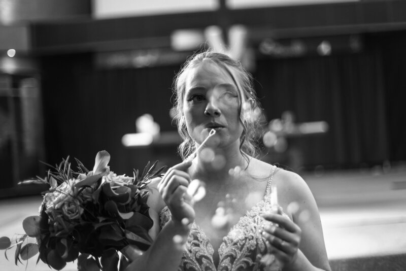 Bride holds bouquet and blows bubbles toward the camera