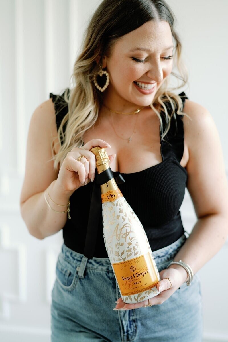 Wedding planner in Houston smiling with a bottle of champagne.