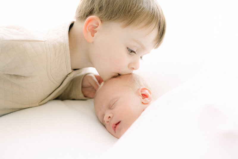 Toddler boy kisses newborn baby brother's head during session with Indianapolis newborn photographer Brittney Lear
