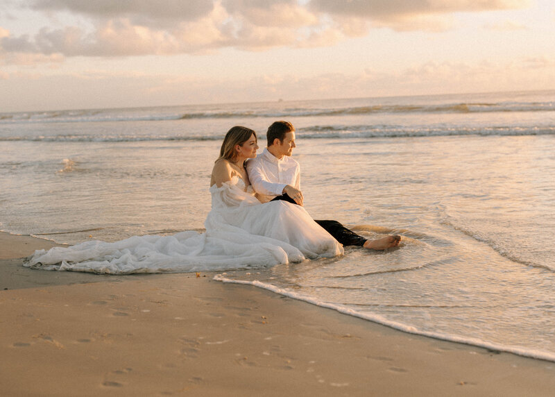 bride and groom sitting on beach