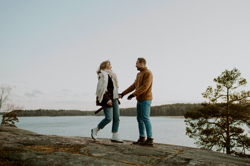 Kihlapari seisoo ja pitää kädestä kiinni Kivenlahden kallioilla Espoossa