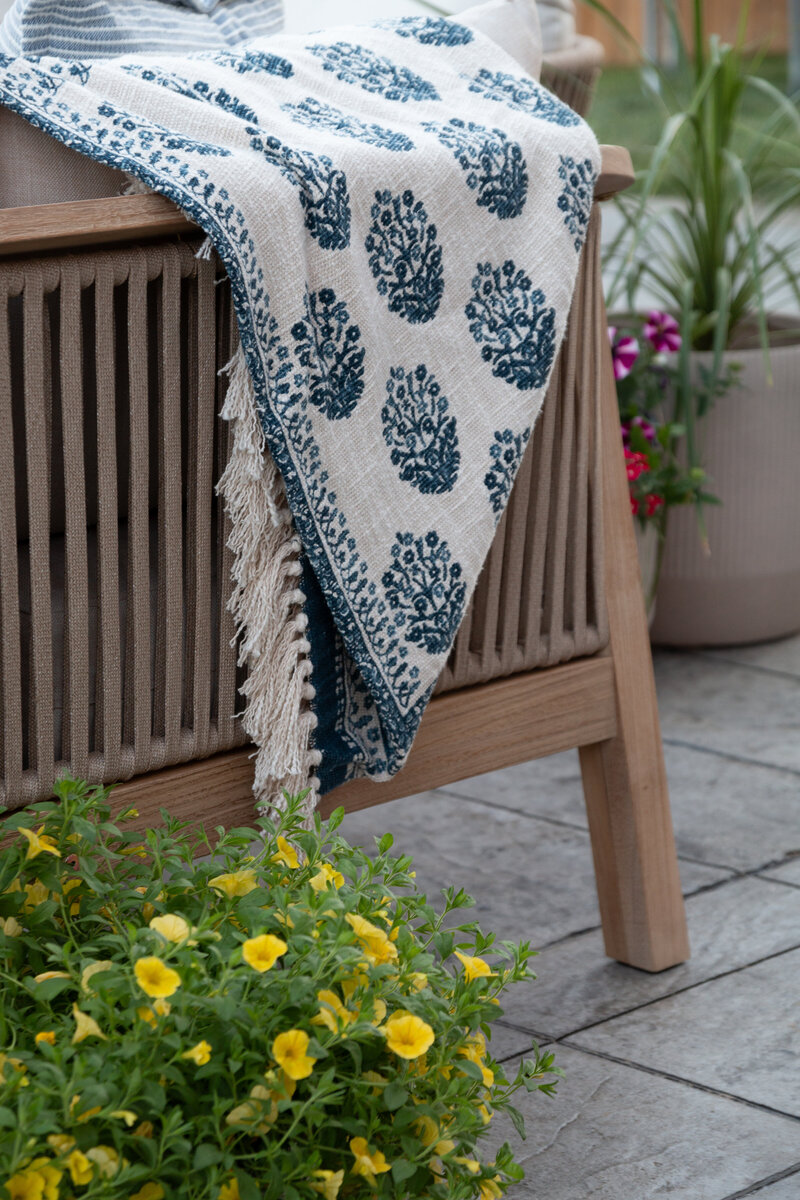close up of an outdoor sofa with a draped blue and white throw