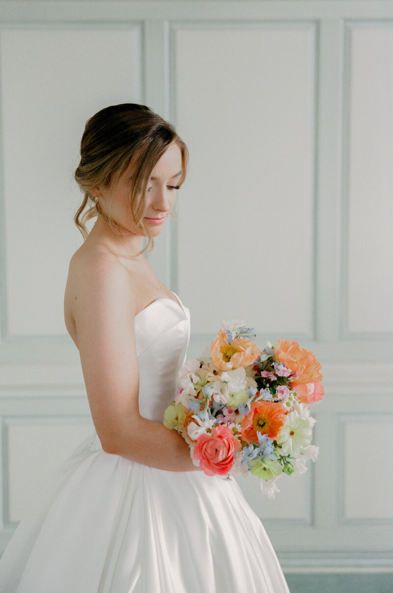 Wedding at the Estate at River Run in Maidens, VA | Wedding Photographer in Richmond | bride looking down at her colorful wedding bouquet in her Richmond wedding venue