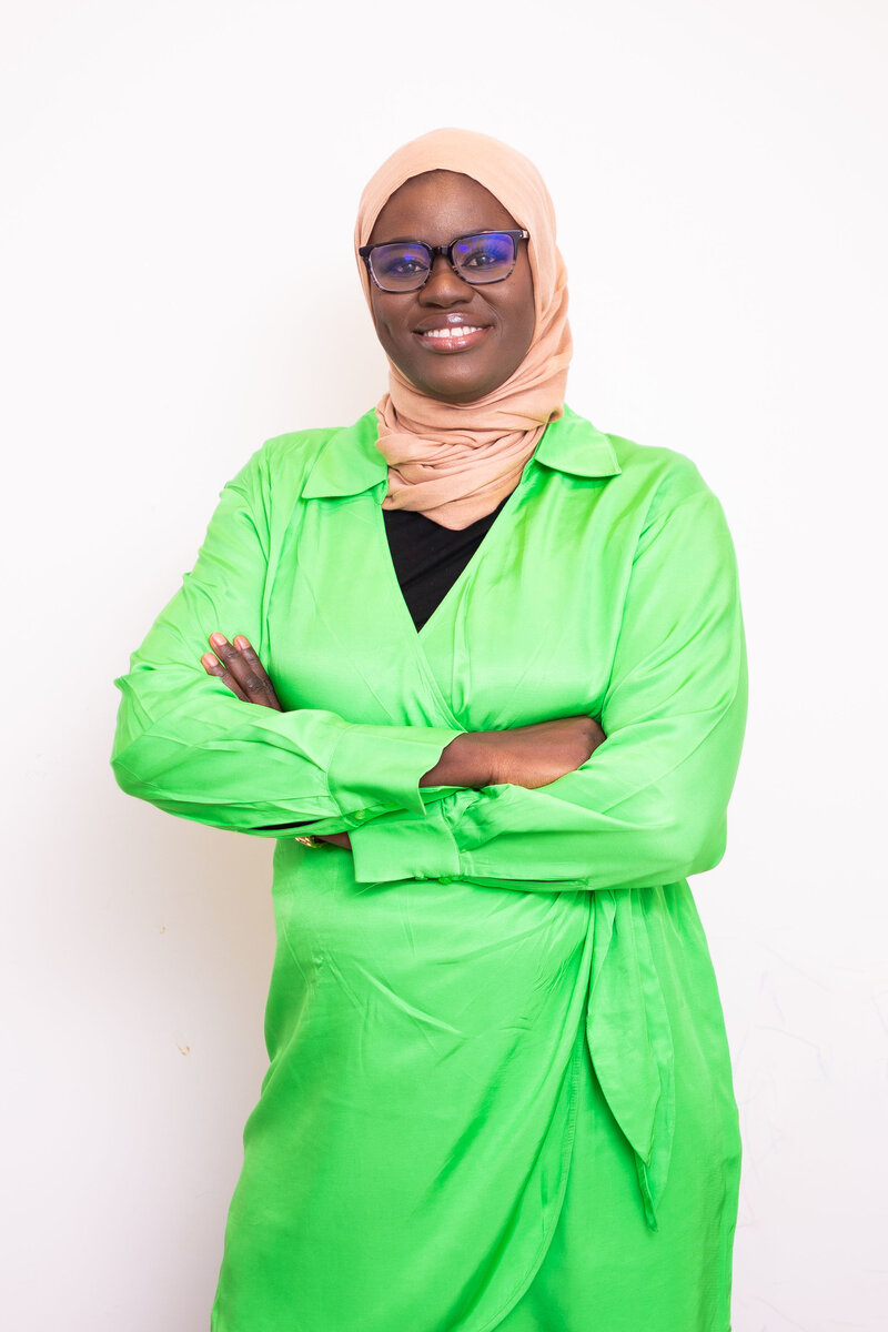 Picture of Isatou Bittaye Jobe, a grant writing consultant, wearing a lime green tunic and smiling confidently. 