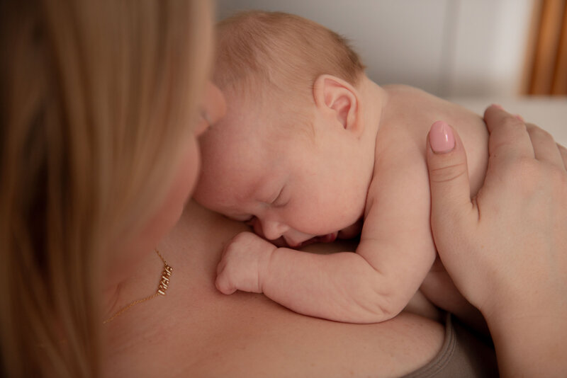 mother snuggling her baby wearing a necklace that says mama