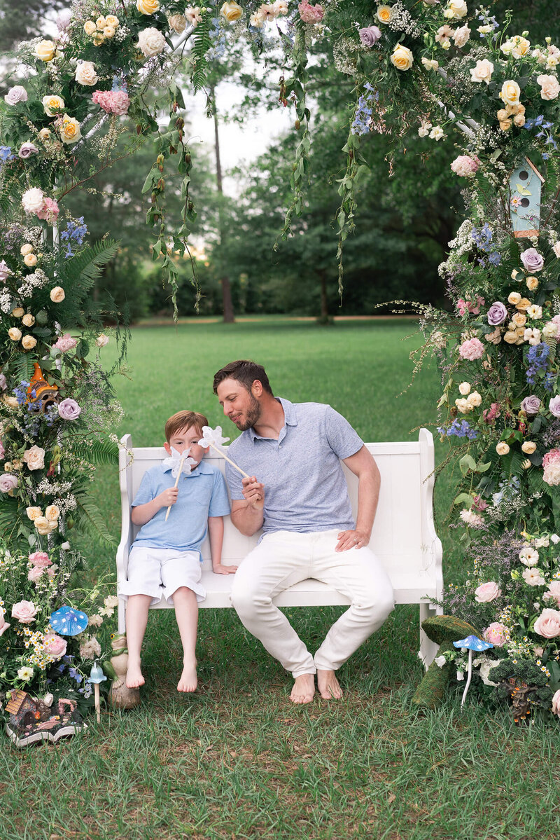 dad and son blow pinwheels in family portrait in Houston Texas by family photographer Swish and Click Photography