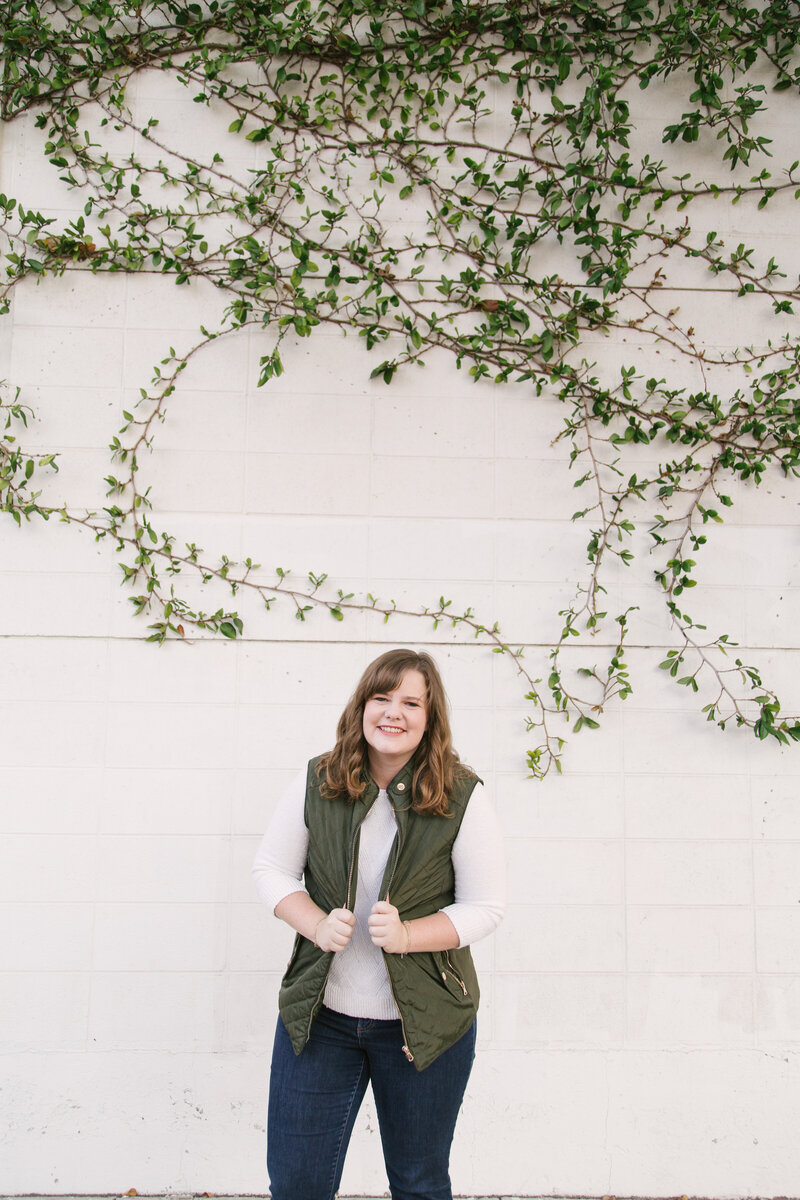 Realtor, Lindsey Drewes, smiles in front of ivy covered exterior wall