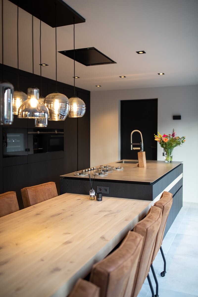 Een stijlvolle combinatie van koken en leven, met een uitnodigende houten eettafel aan het eiland en warme verlichting.
