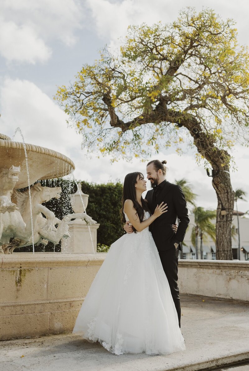 bride and groom pose next to fountain