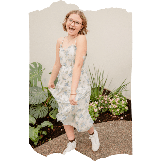 Senior girl dances in butterfly house as photographer captures her authentic self.