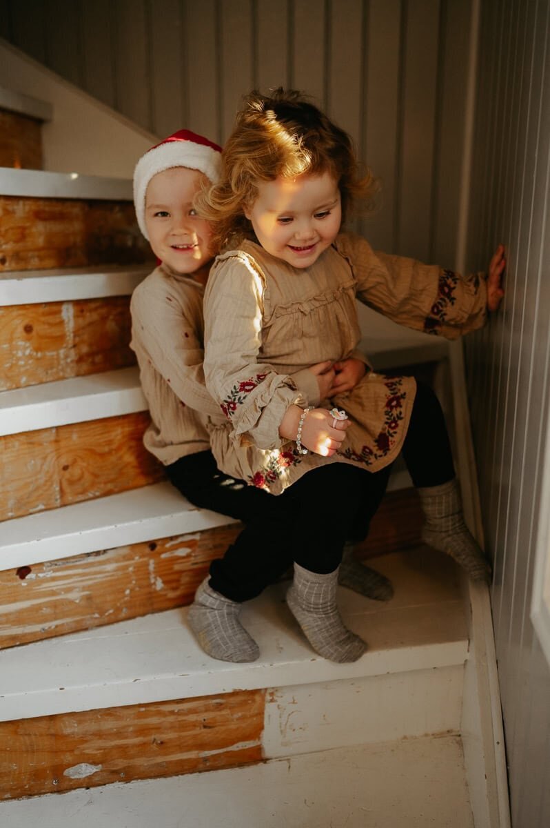Två syskon sitter i en trapp och tjejen sitter i killens knä.
