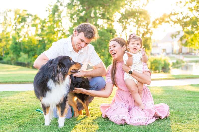 Rosse petting dog while holding her baby whos is smiling with dad in family photo
