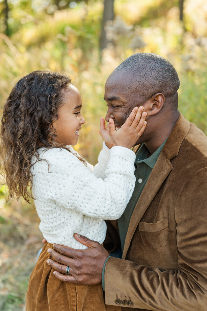 a daughter squeezes her dads cheeks