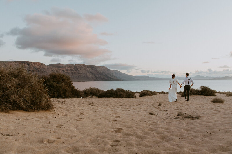 Couple walking down beach at sunset