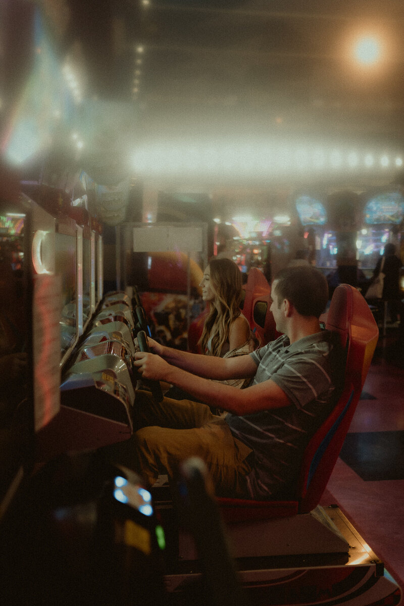 couple sitting on a skateboard facing each other staring into one anothers eyes, the girl holding the guys face with her hands