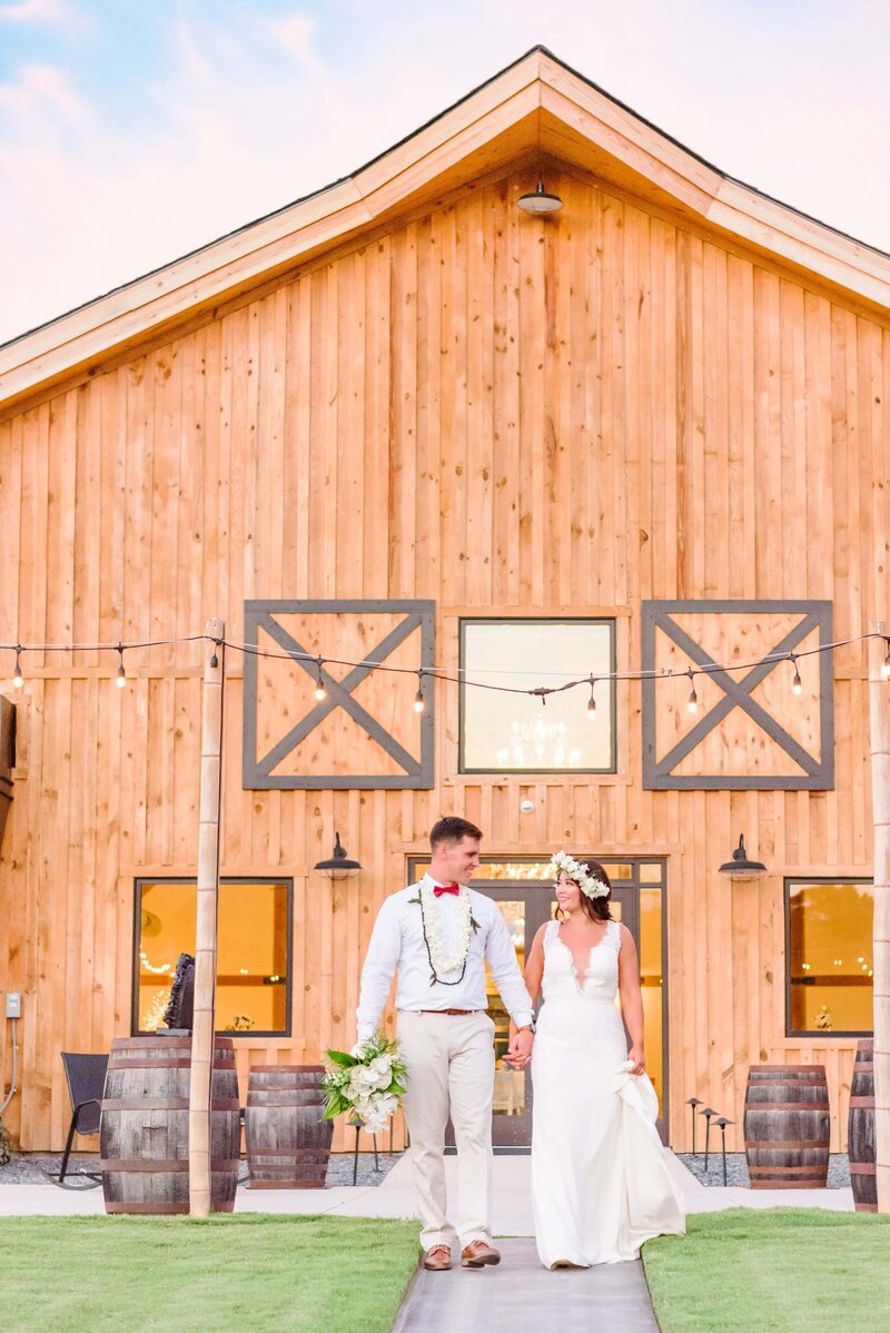 A bride and groom walk away from the barn at Camelot Meadows.