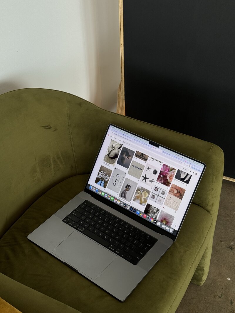 Opened macbook on olive green chair showcasing pinterest pins
