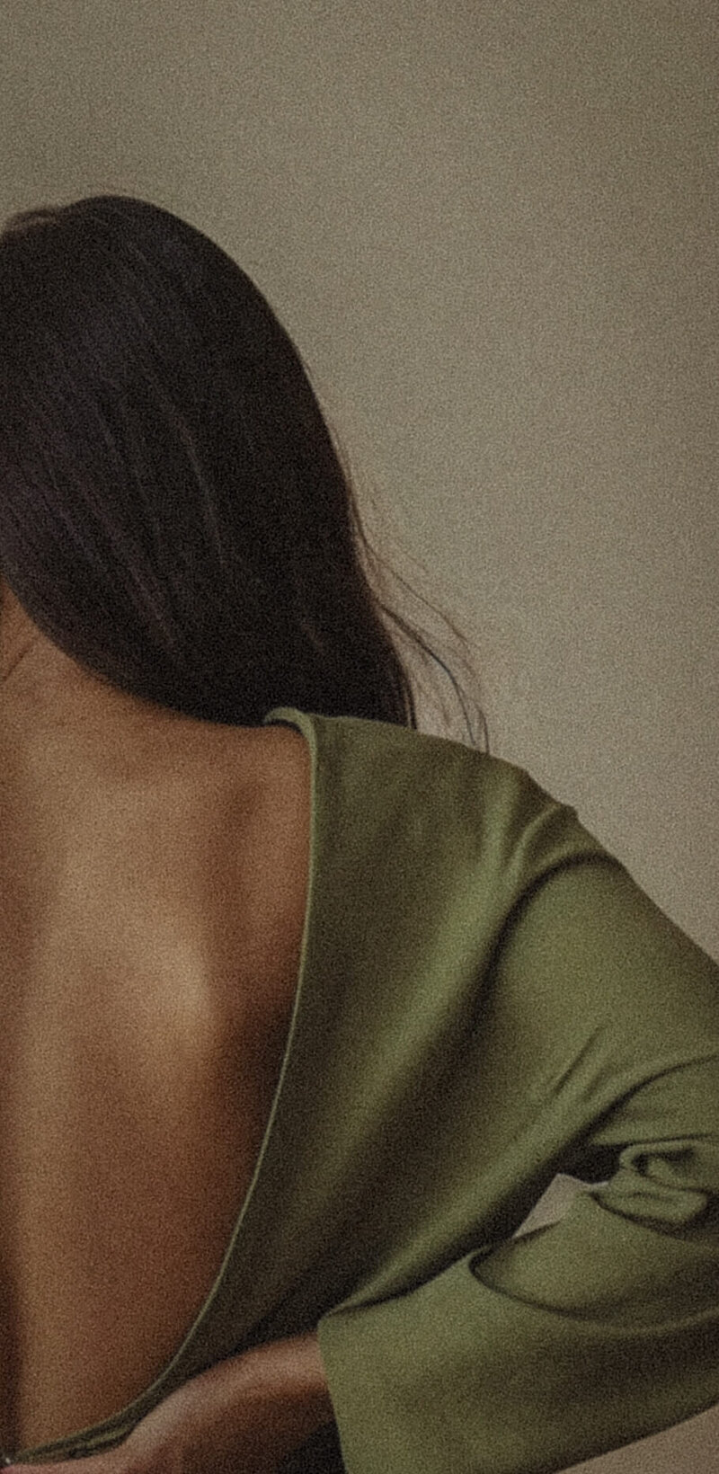 Woman in an open-back green dress, symbolizing grounded energy and body awareness.