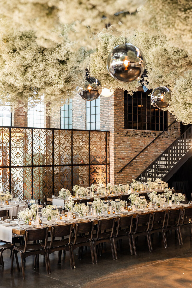 Elegant wedding reception setup with hanging floral decor and industrial elements