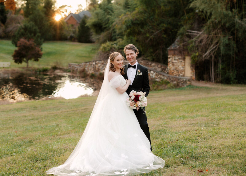 November wedding at Graylyn Estate, designed and planned by Charming Carolina — bride and groom posing next to the estate’s cobblestone bridge during golden hour portraits.