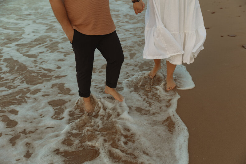 couple holding hands on beach in pei