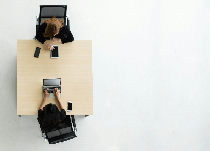Two professionals collaborating at a shared desk with laptops and notebooks, symbolizing strategic partnership.