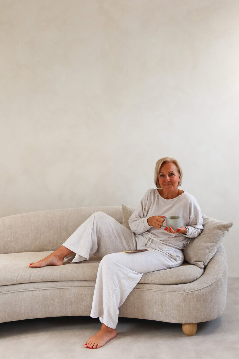 Sober coach for women in midlife, sitting comfortably on a neutral sofa.