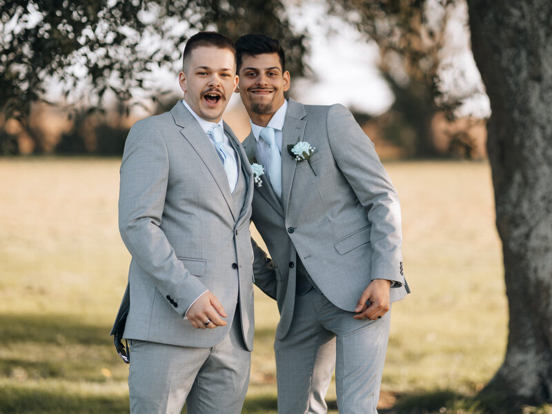 Groom and best man messing around laughing outside