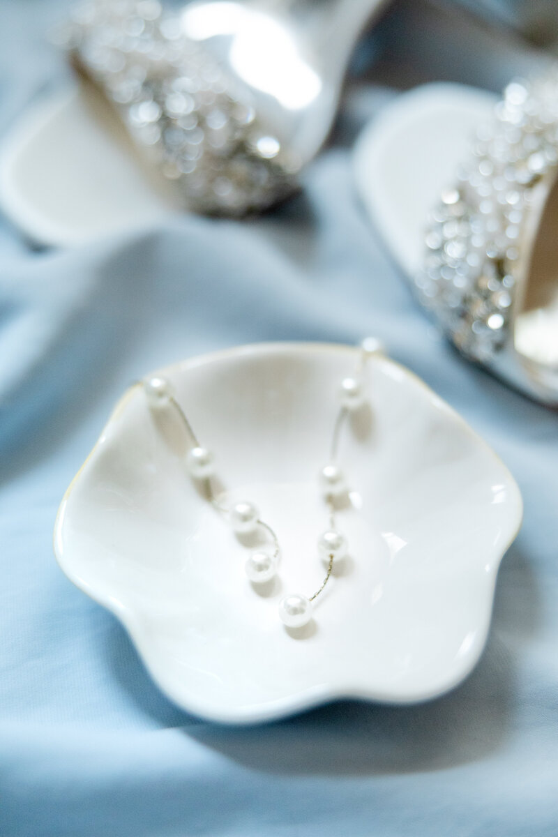 wedding shoes and necklace on a blue cloth