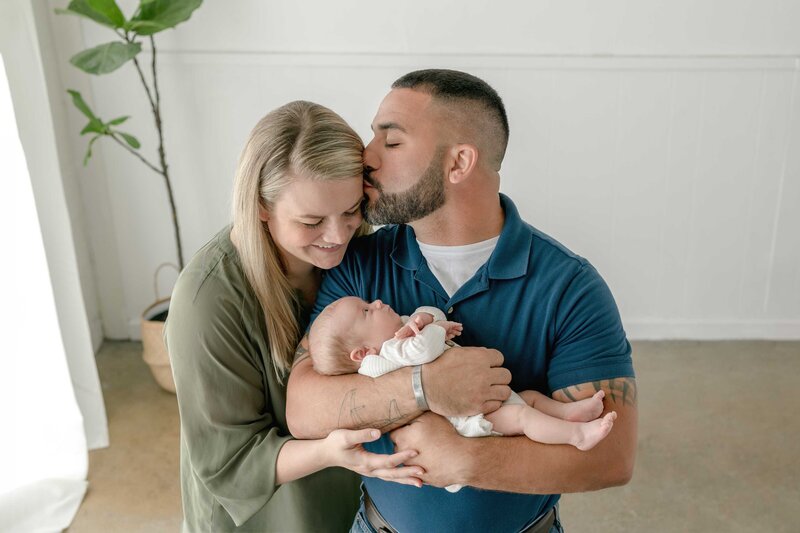 Backlit image of new parents holding and looking down at their baby boy